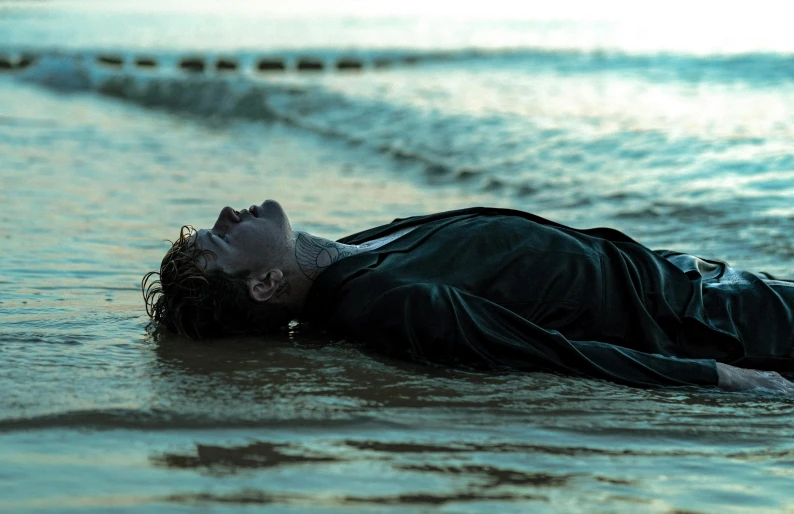 a man laying on the ground in the water