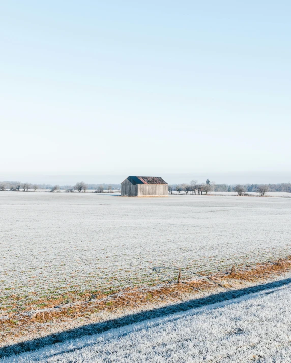 the barn is standing alone in the snowy field