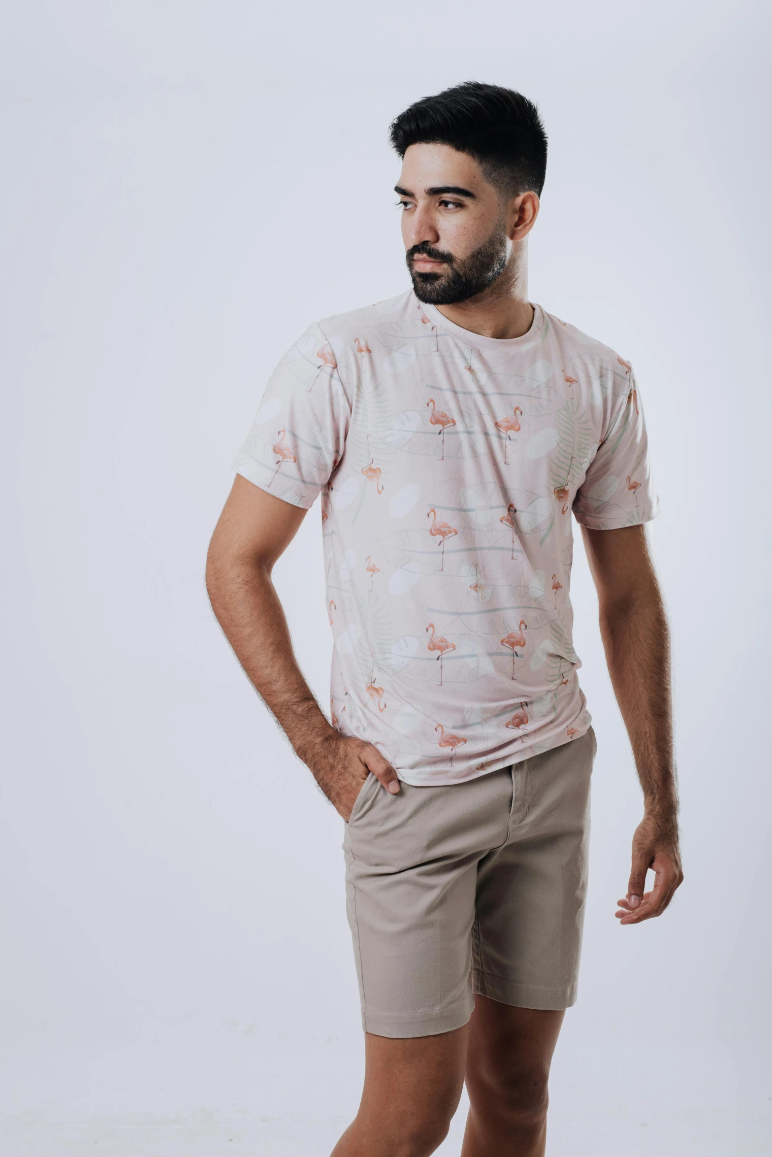 young man standing wearing white shirt and tan shorts