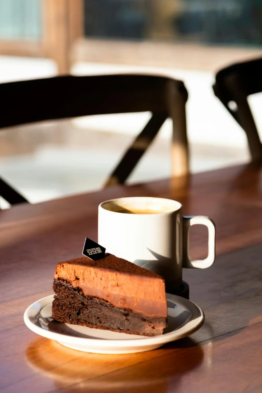 a piece of chocolate cake on a plate with a cup of coffee