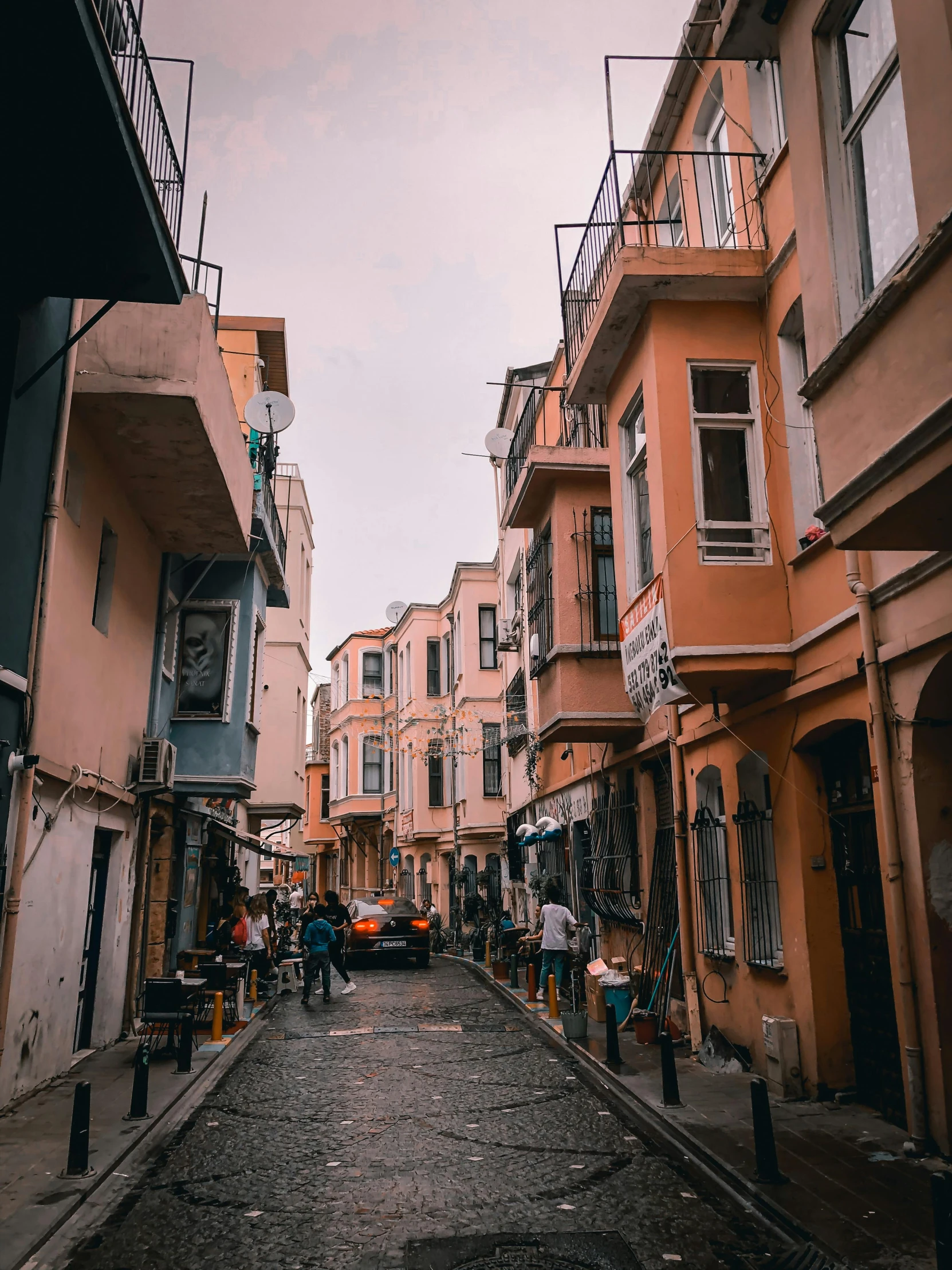 narrow alley with people and a car in between