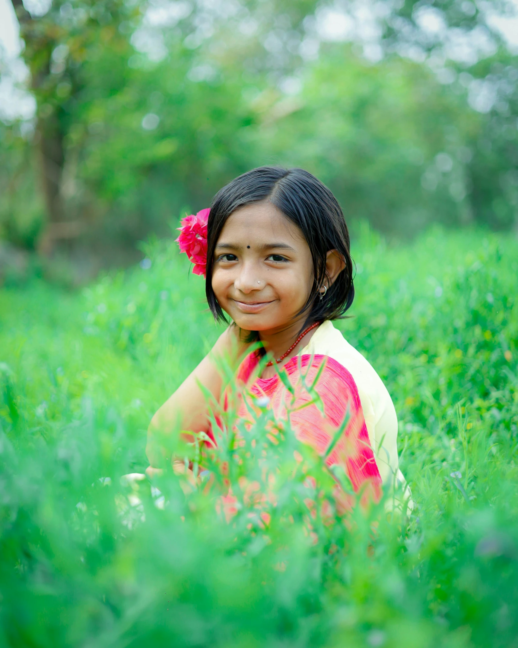 a girl sitting in grass, looking into the camera