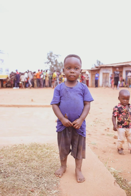 a small child stands on a dirt path outside