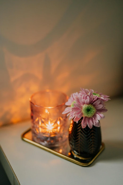 the flower in the glass vase has a candle on top