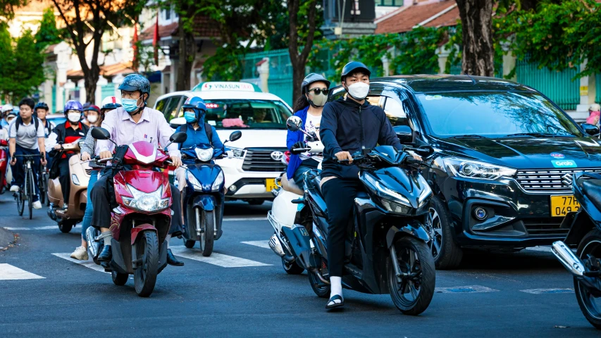 many people riding scooters on a street