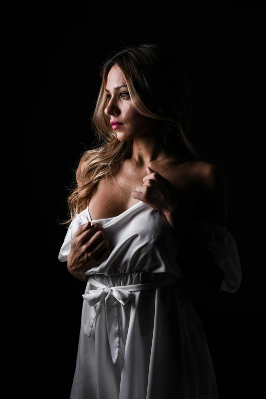 a beautiful woman posing in white clothing against a black background