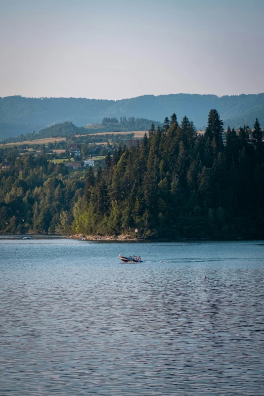 a boat sitting on top of a lake surrounded by trees