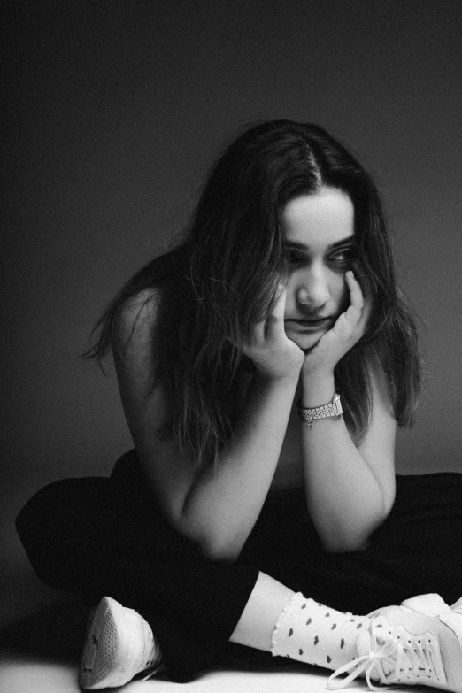 a woman sits on the floor, holding her hands to her face