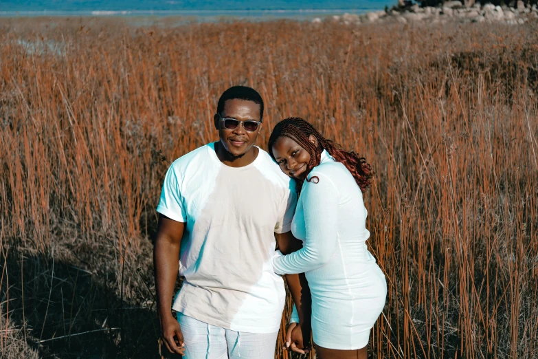 a couple is standing in front of a wheat field