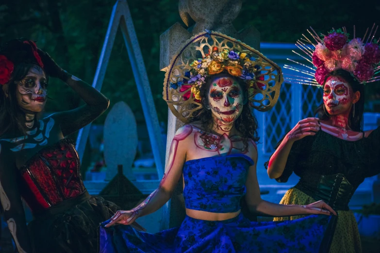 three women with skeleton makeup and flower headpieces pose for the camera