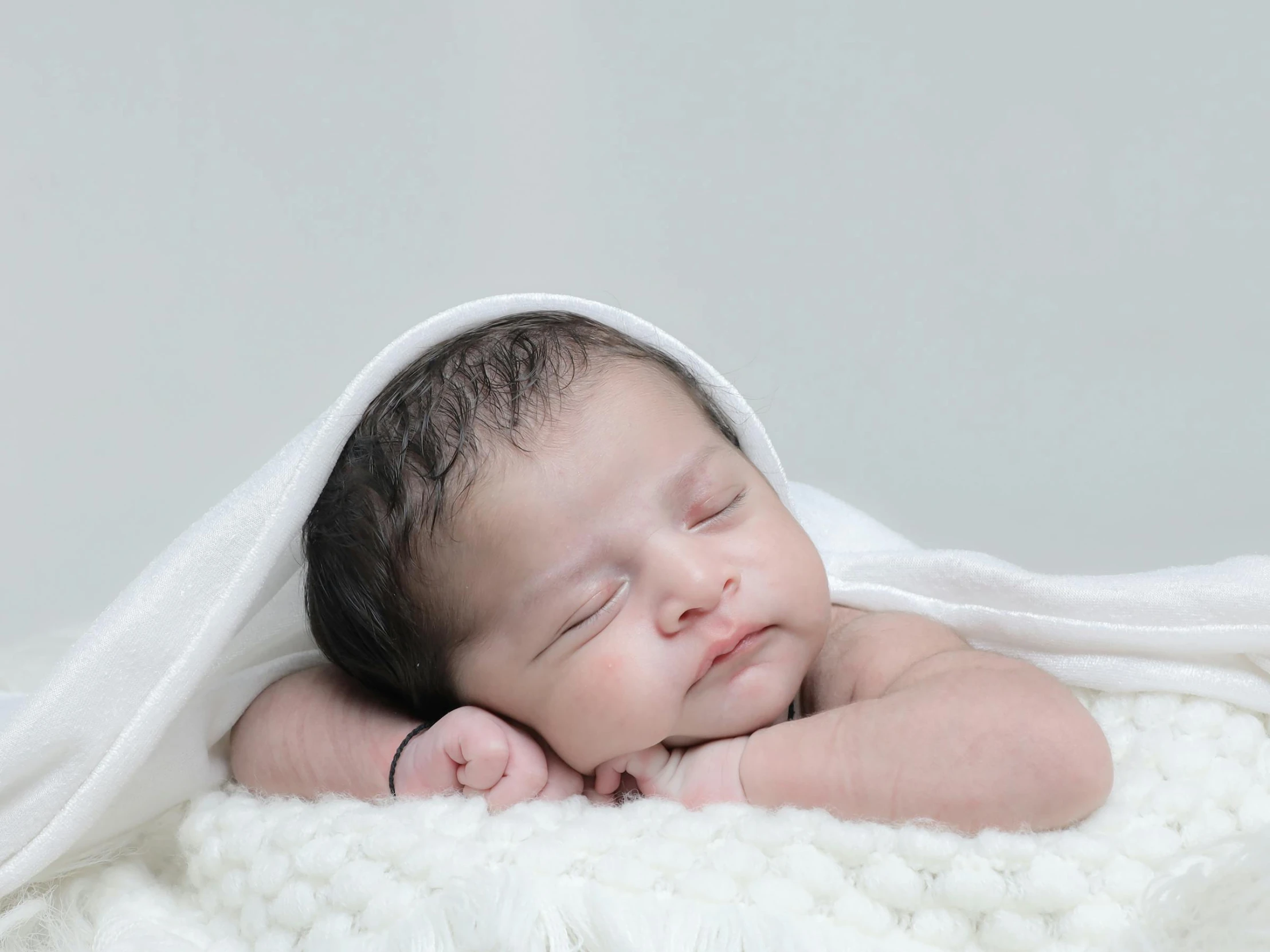 a close - up po of a baby covered in white sheets