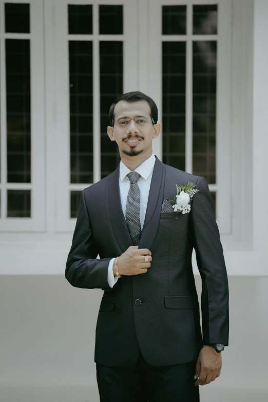 a groom in a suit and tie holding his bowtie