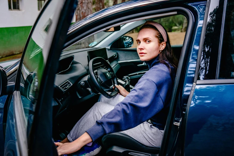 a woman sits inside of a blue car in the back seat