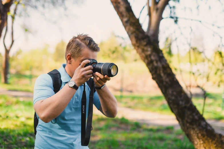 a man with a camera near trees in the daytime