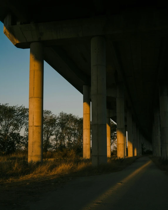 a car sits on the road underneath some very tall concrete pillars