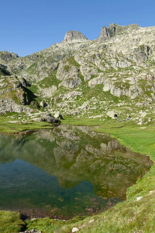 a view of some mountains with water and grass