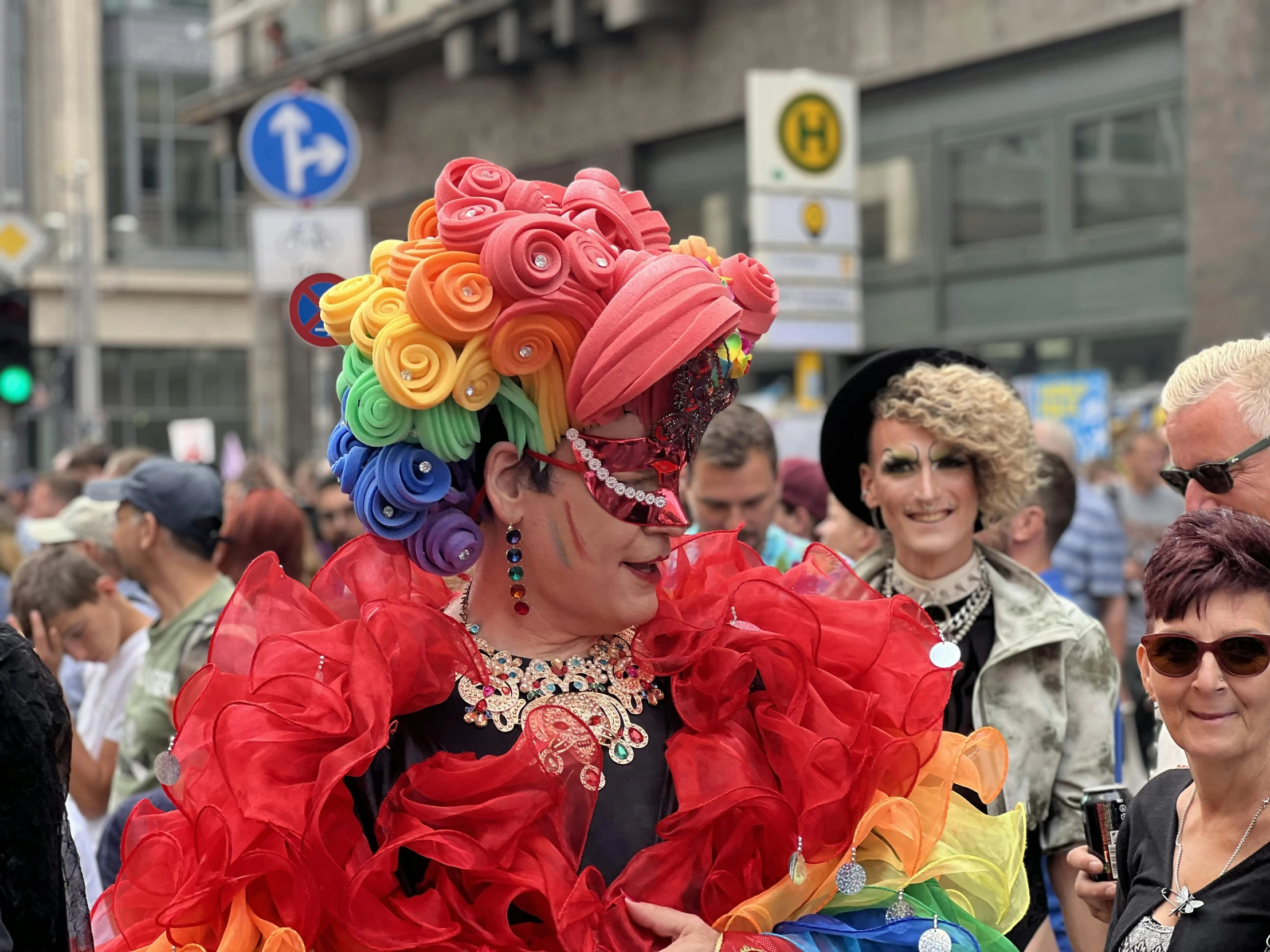 a woman dressed in a bright colored wig and feather dress