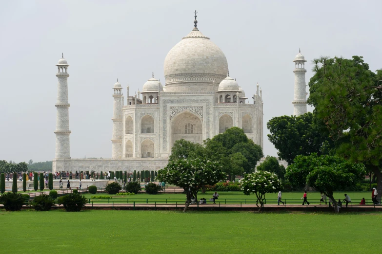 a white building with several arches stands near a grassy field