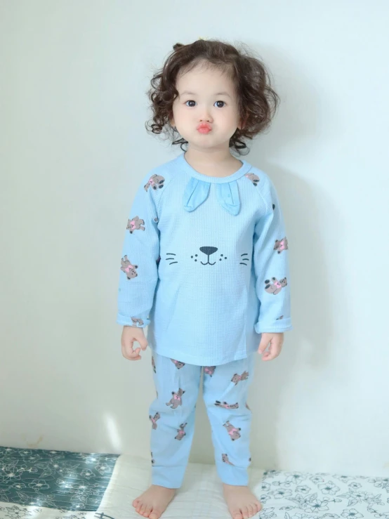 a little girl in pajamas standing up