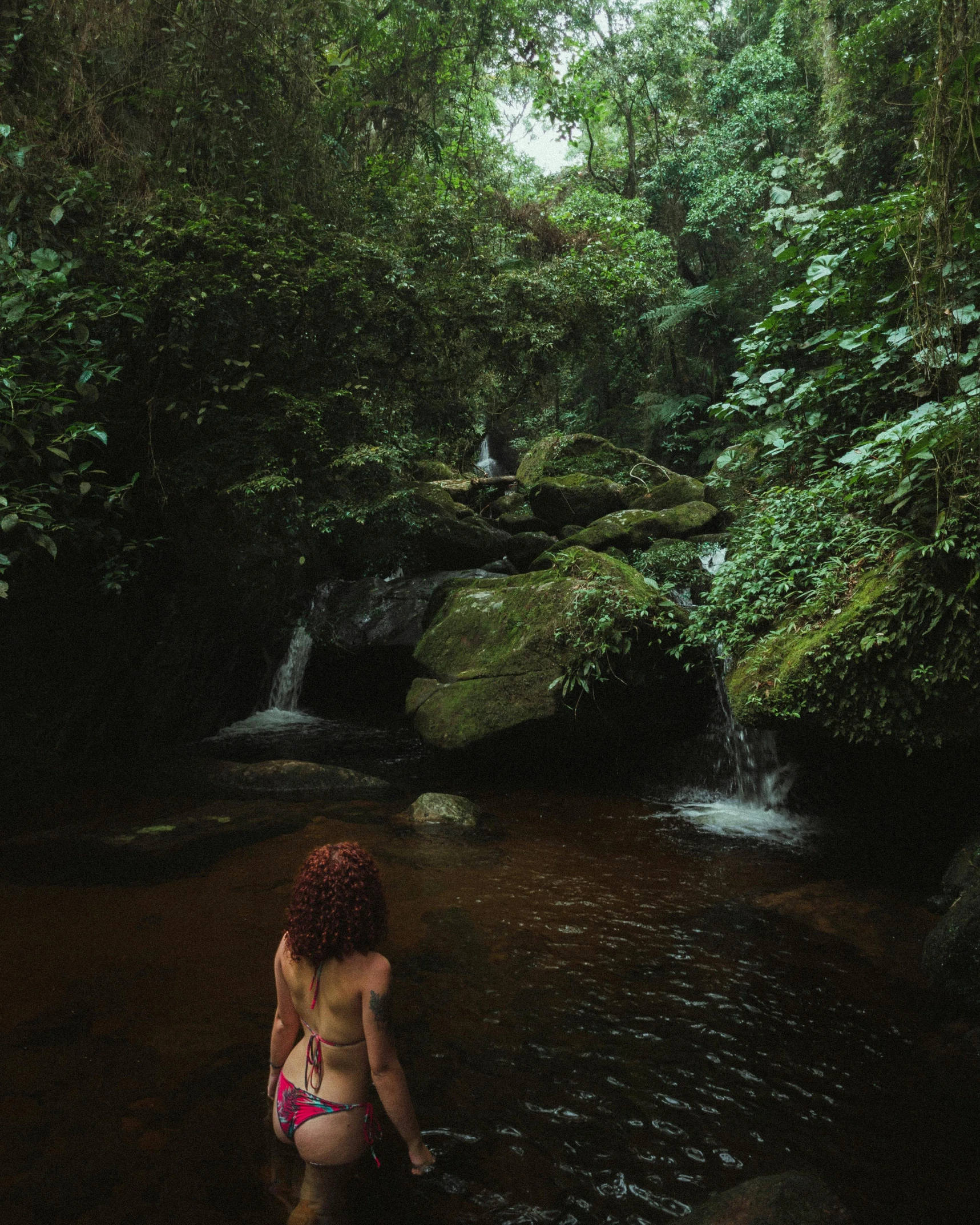 a woman in a pink bikini standing in a stream