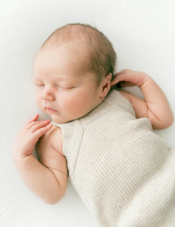 a baby laying on its back sleeping on top of a blanket