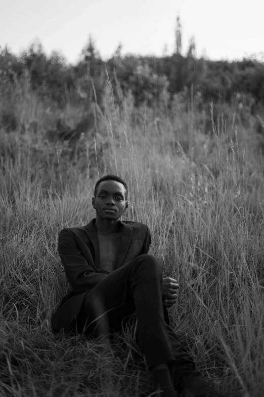 a man sitting in the grass looking at soing