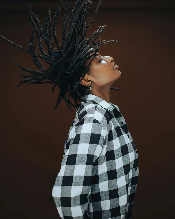 a woman with dreadlocks standing against a brown wall