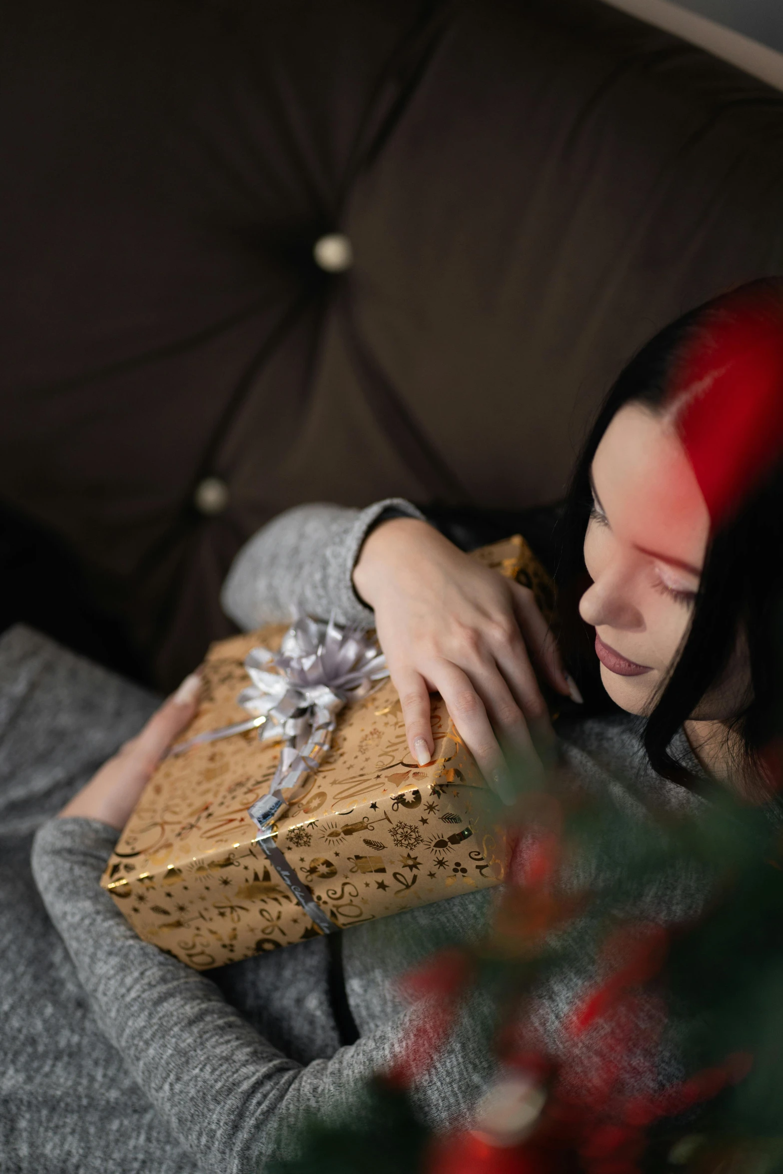 a woman sits on a couch holding a wrapped present