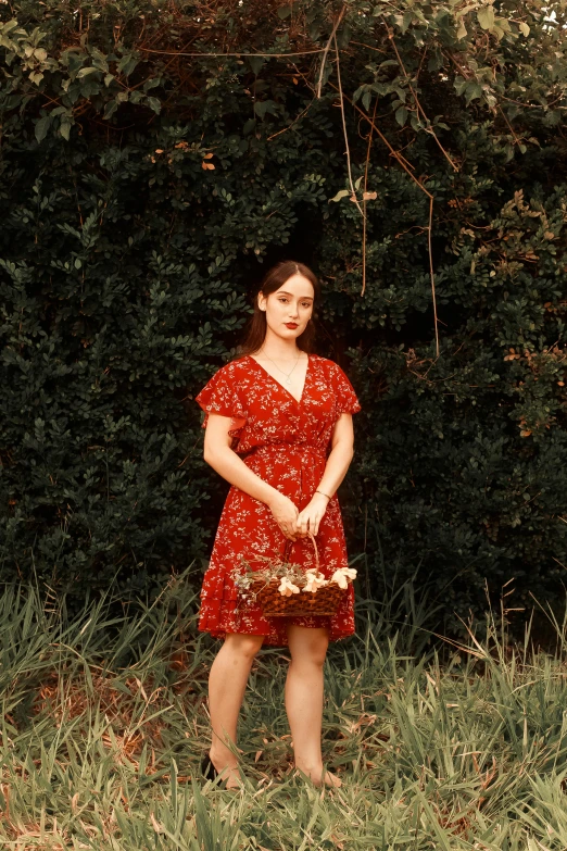 a young lady in a red dress standing against trees