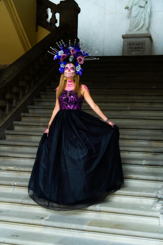 woman in purple and black dress on stairs with sculpture