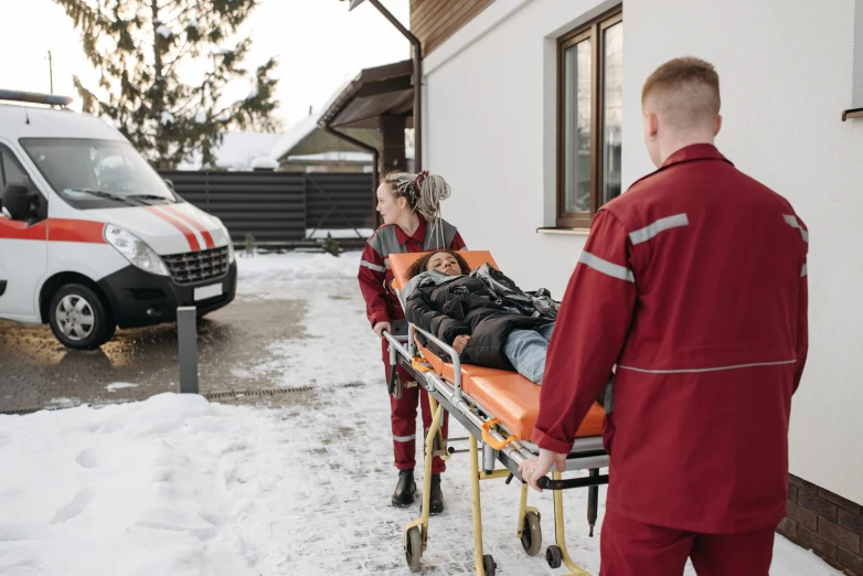 children carry the person in a medical stretcher on a small sled