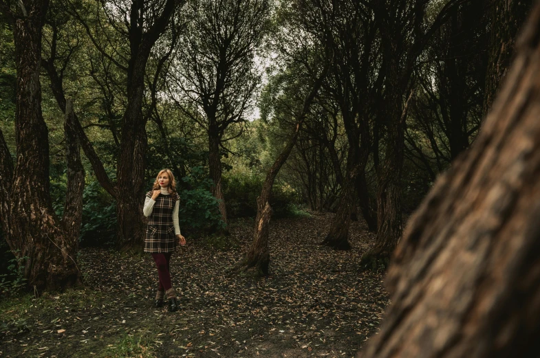 the woman in a plaid is standing by the trees