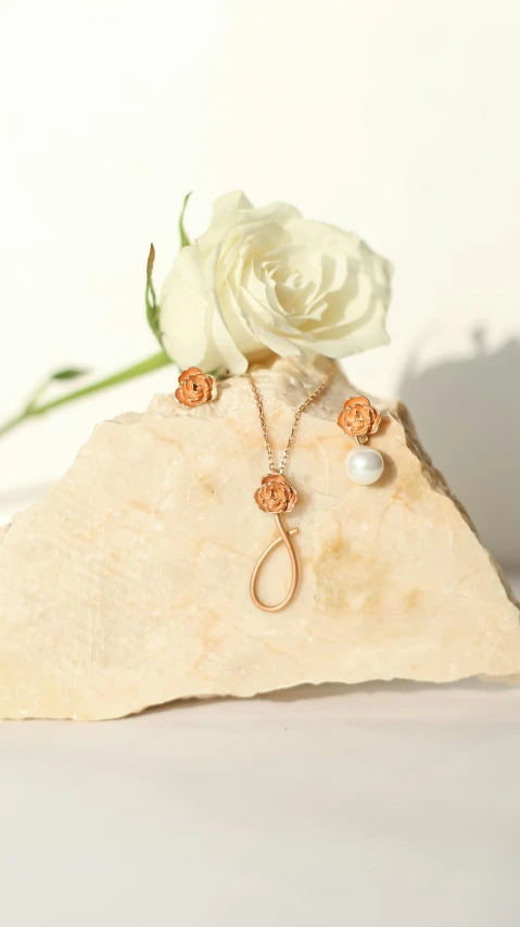 two pieces of jewelry on a rock and a flower