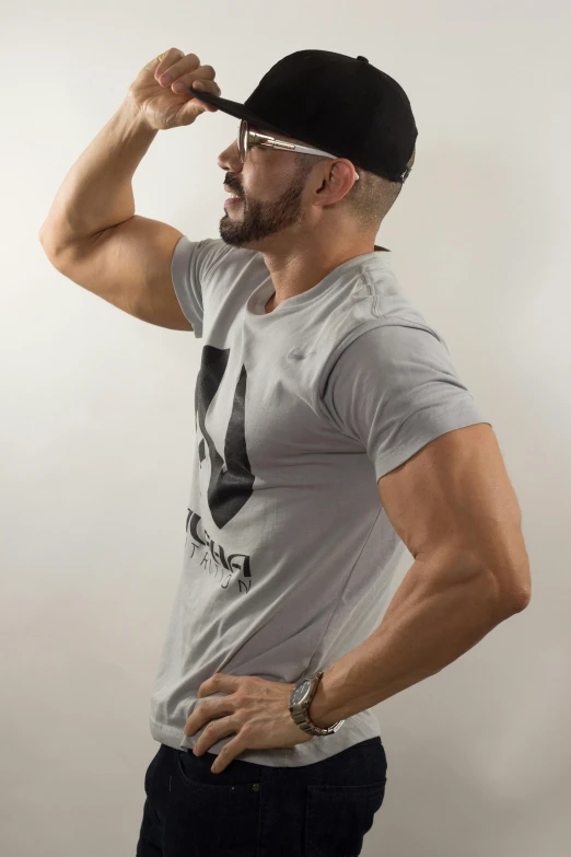 man wearing a gray shirt, cap, and black hat