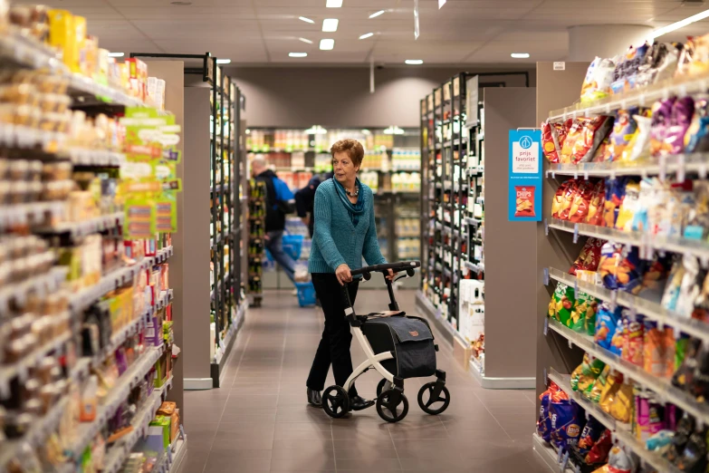 a woman hing a stroller through a grocery store aisle