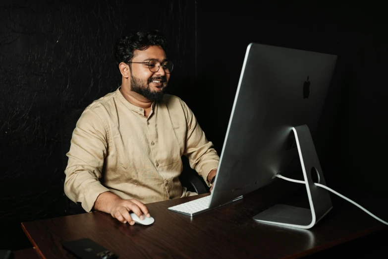 man in front of monitor holding mouse and laptop