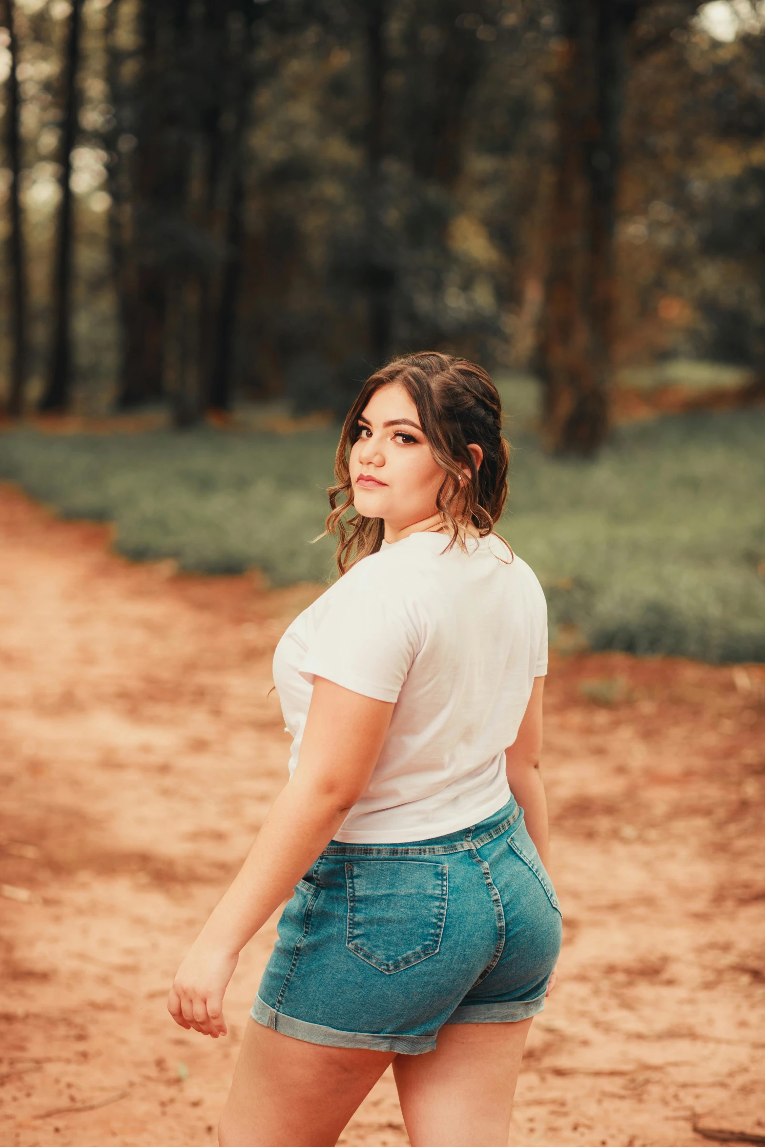 the woman is wearing short blue shorts while in the woods