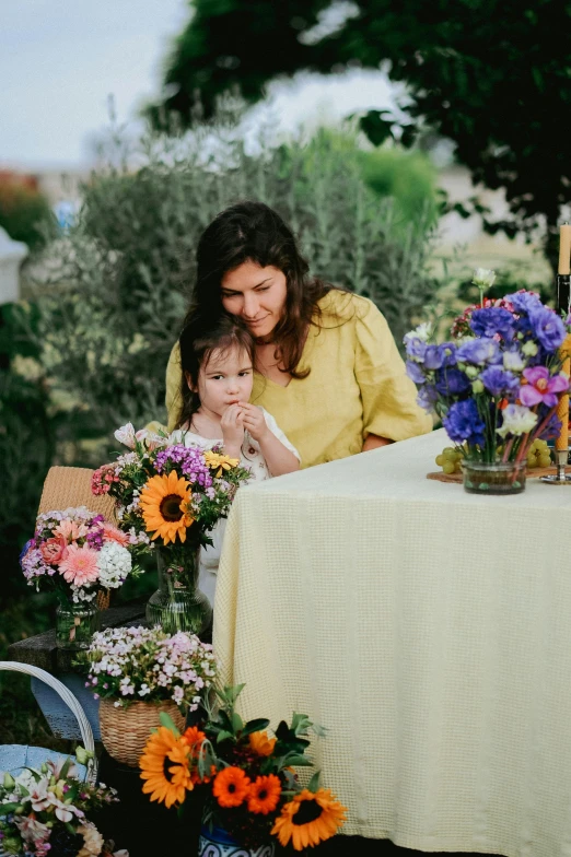 a woman sitting next to a child and flowers