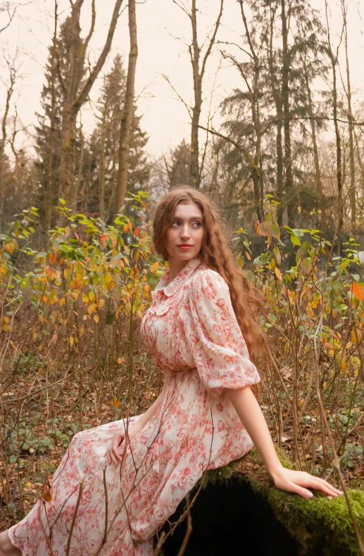 a woman sits on a stump in a grassy forest