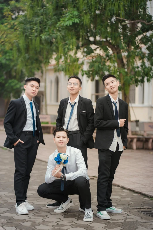 three men pose in front of a green tree