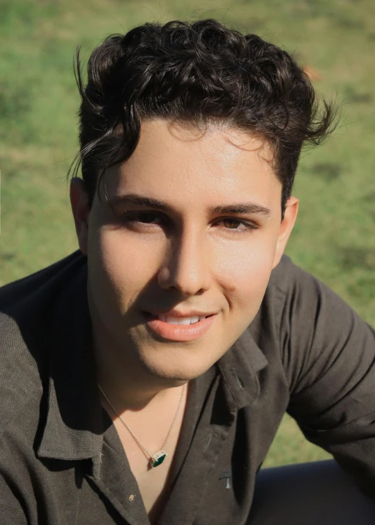 a man posing in front of some green grass