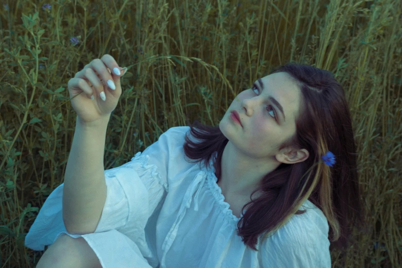 a woman sits in tall grass blowing bubbles