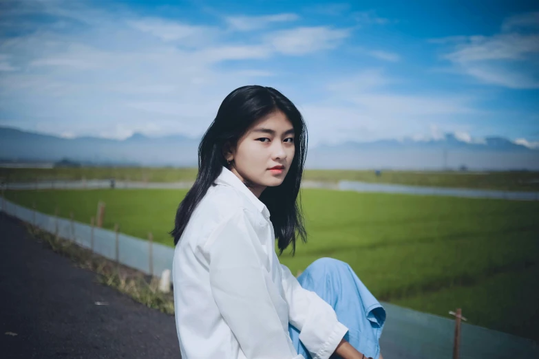 a girl sitting on the road and looking at her camera