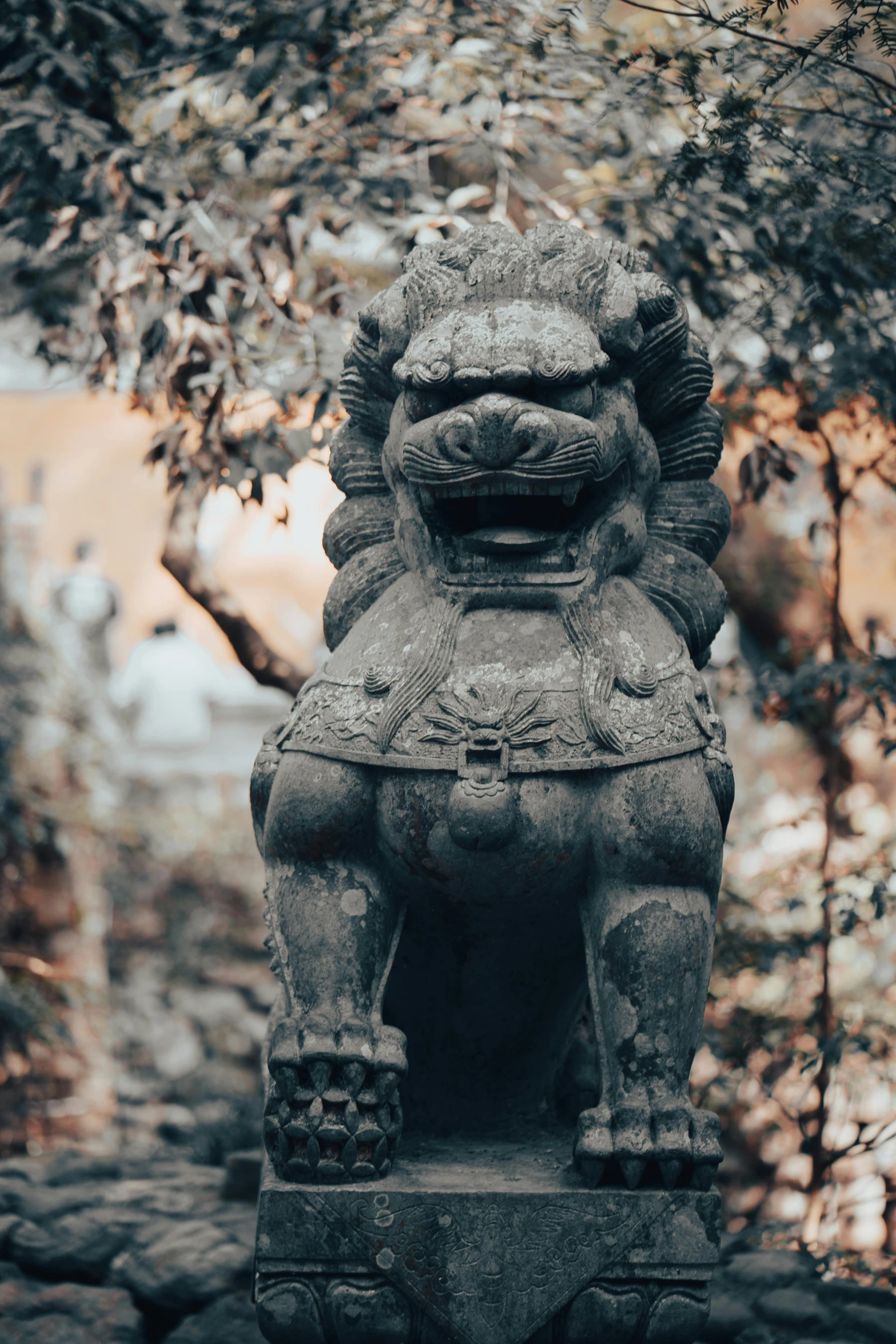 statue sitting under a tree in the middle of a park