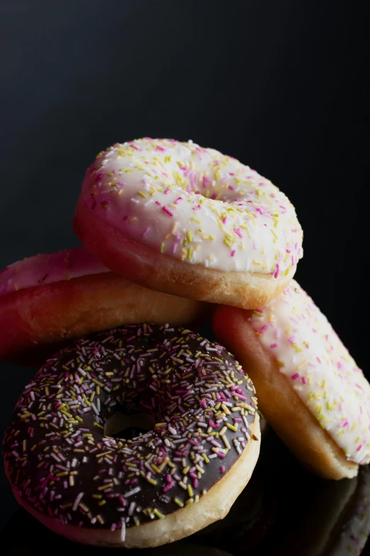 four donuts are grouped together and topped with sprinkles