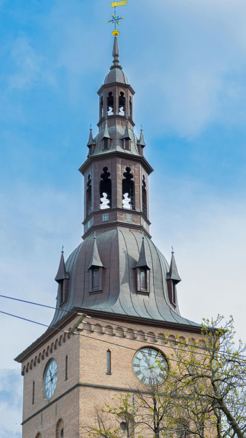 the bell tower has two clocks and is surrounded by a tree