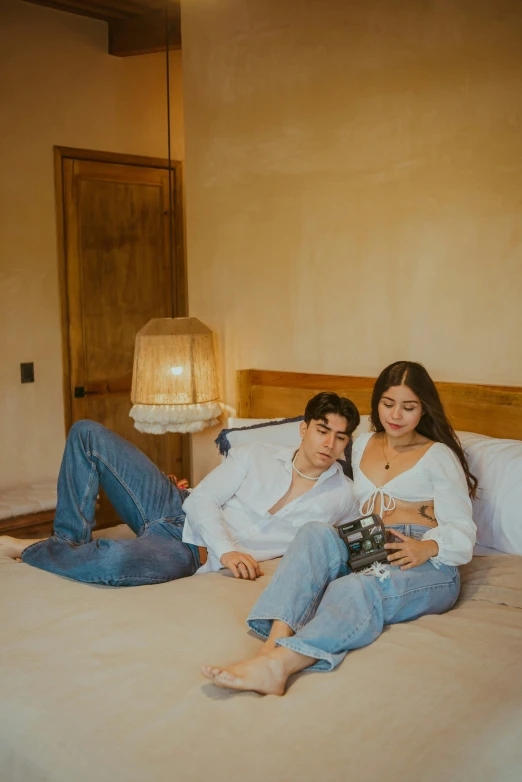 two people sitting on a bed and one woman holding a bottle