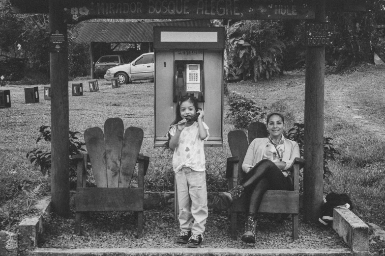 two children stand by a small cell phone booth