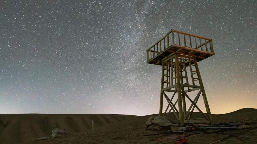 a wooden tower near the desert with stars overhead