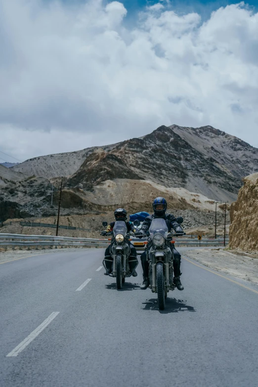 three motorcycles with helmets on their back riding down the street